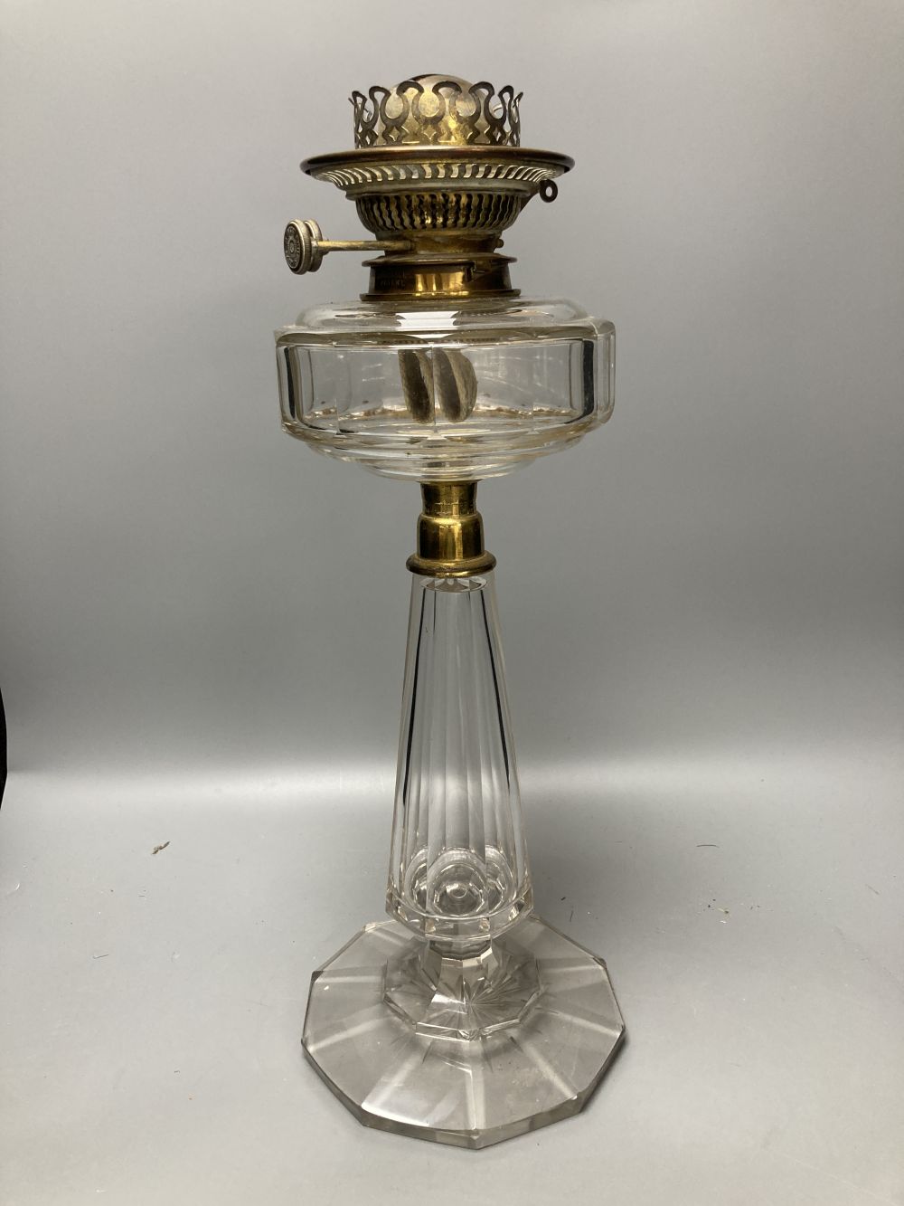 A late 19th century cut glass oil lamp with floral embossed shade, 61cm high including shade